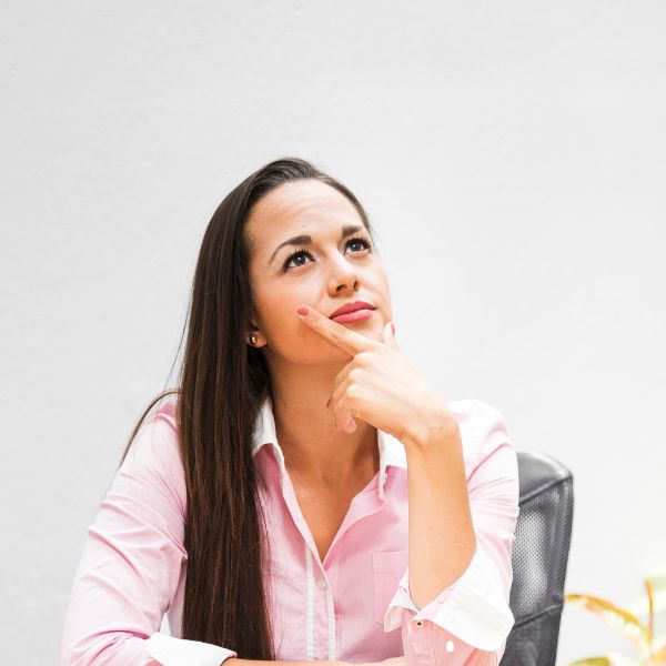 Woman sitting, looking upwards and deep in thought