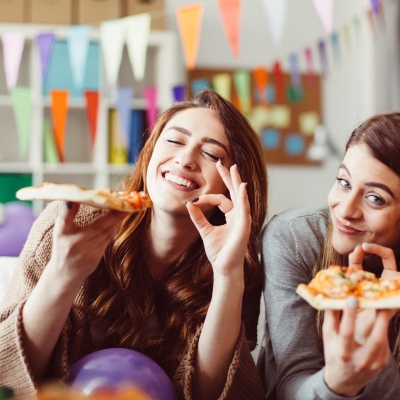 Two women employees enjoying pizza lunches offered by employers as fringe benefit