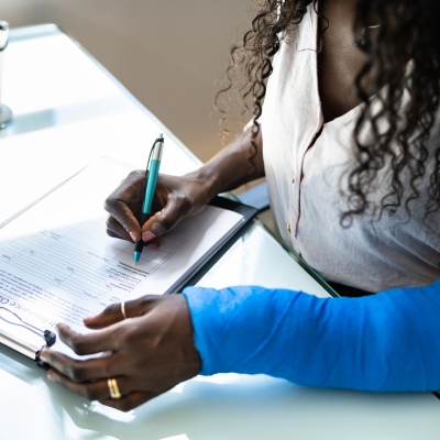 Woman with injury on one hand filling out workers compensation insurance paperwork