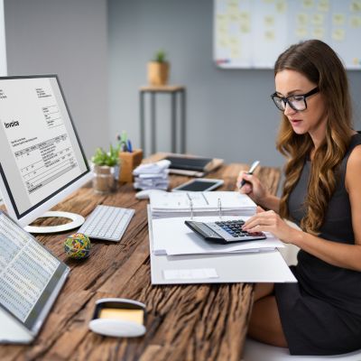 Image showing woman working with a calculator with computer display 